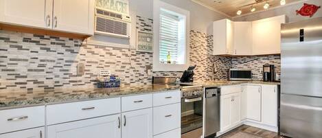 A modern kitchen with white cabinets, a stainless steel refrigerator, and a tiled backsplash.