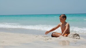 A person sitting on a sandy beach with the ocean in the background. - 50 Steps to Beach Villa Hot Tub 1bd modern cottage (Bradenton Beach)
