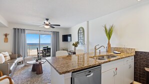 A modern kitchen with granite countertops, a dishwasher, and a dining area with a view of the ocean. - Gorgeous Recently Updated 3rd Floor Direct Beachfront Condo Perfect Location (Gulf Shores)