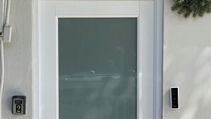 A door with a frosted glass panel, a doorbell, and a mailbox on the wall.