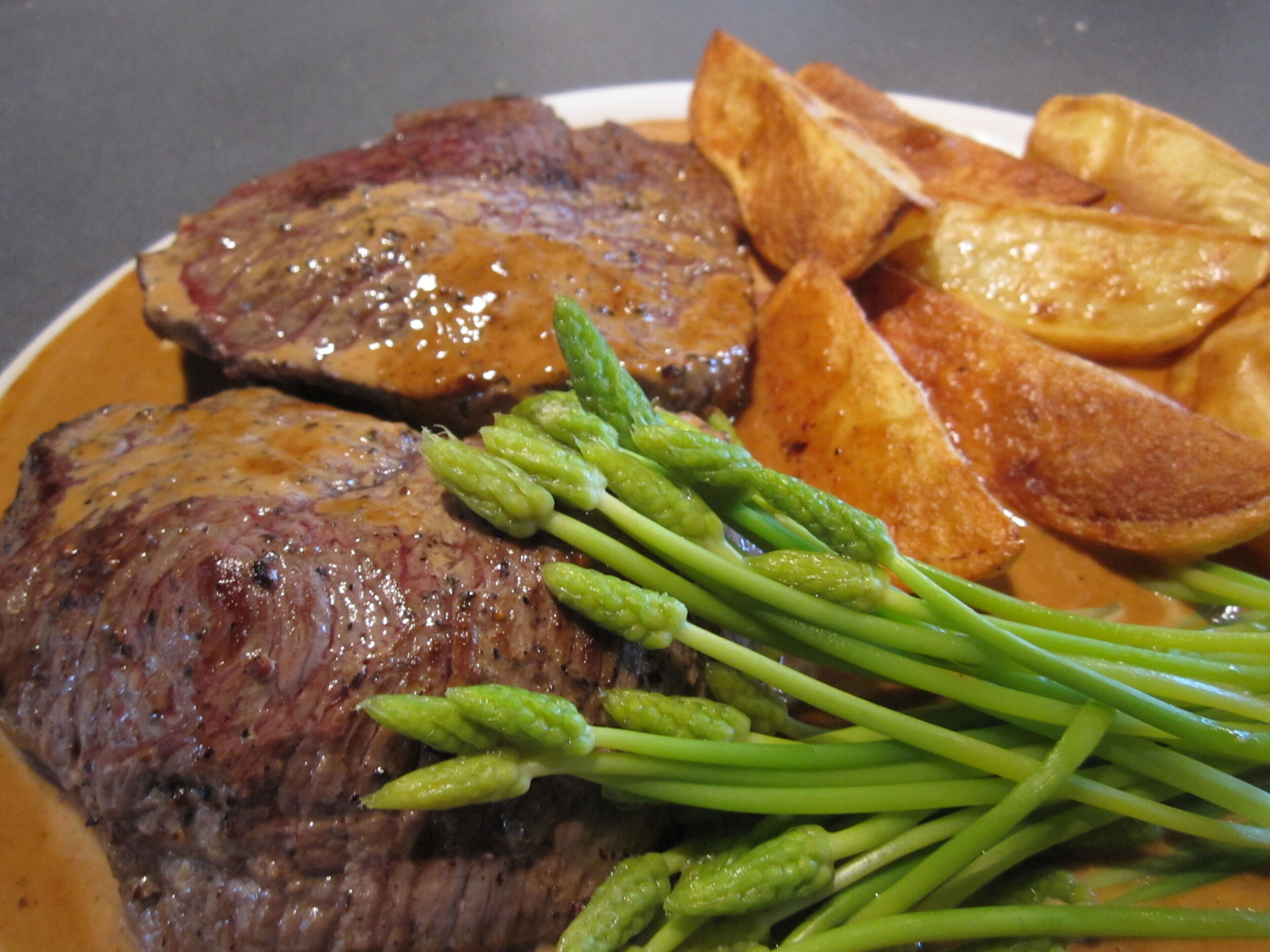 Ein Teller mit Steak, Spargel und Bratkartoffeln.
