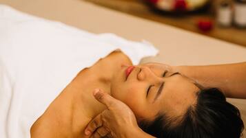 A person lying on a massage table in a spa setting.