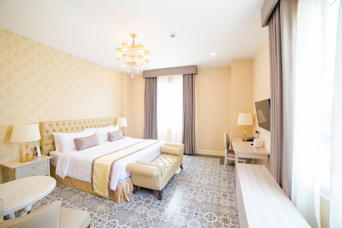 Une chambre d’hôtel avec un grand lit, des tables de chevet, un bureau et une télévision.