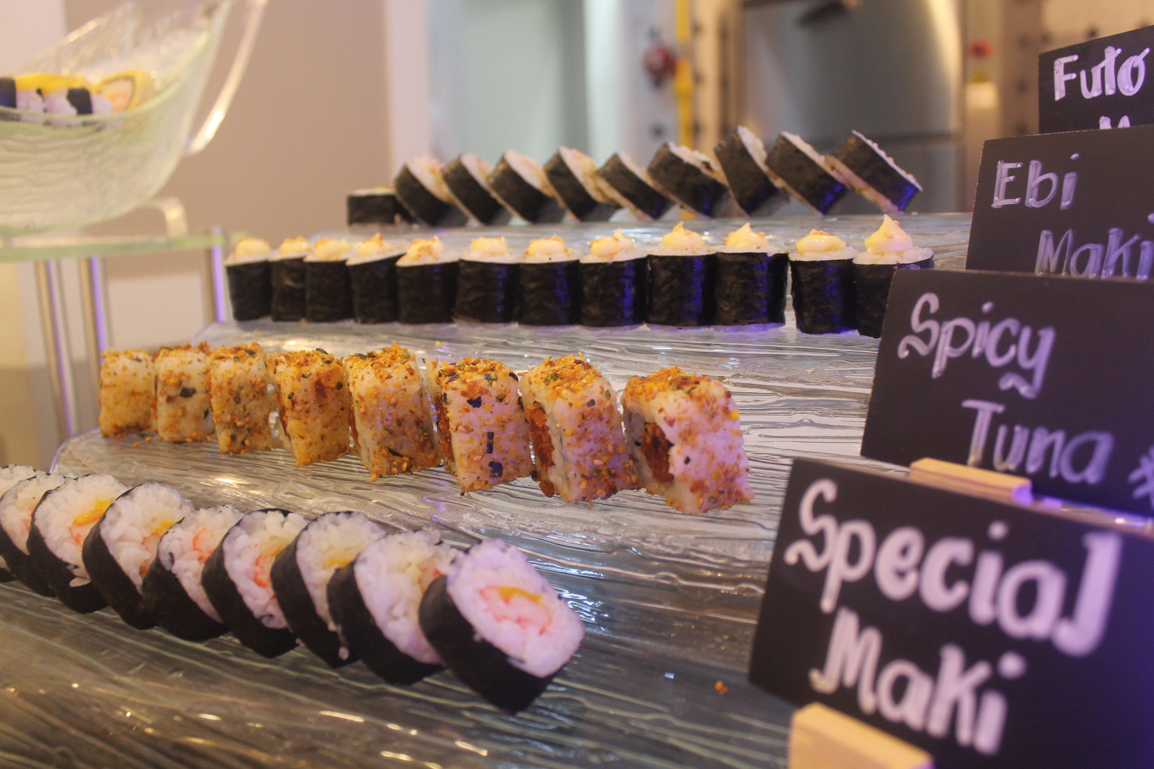 Une présentation de sushis comprenant différents types de sushis et des étiquettes indiquant les différentes saveurs.