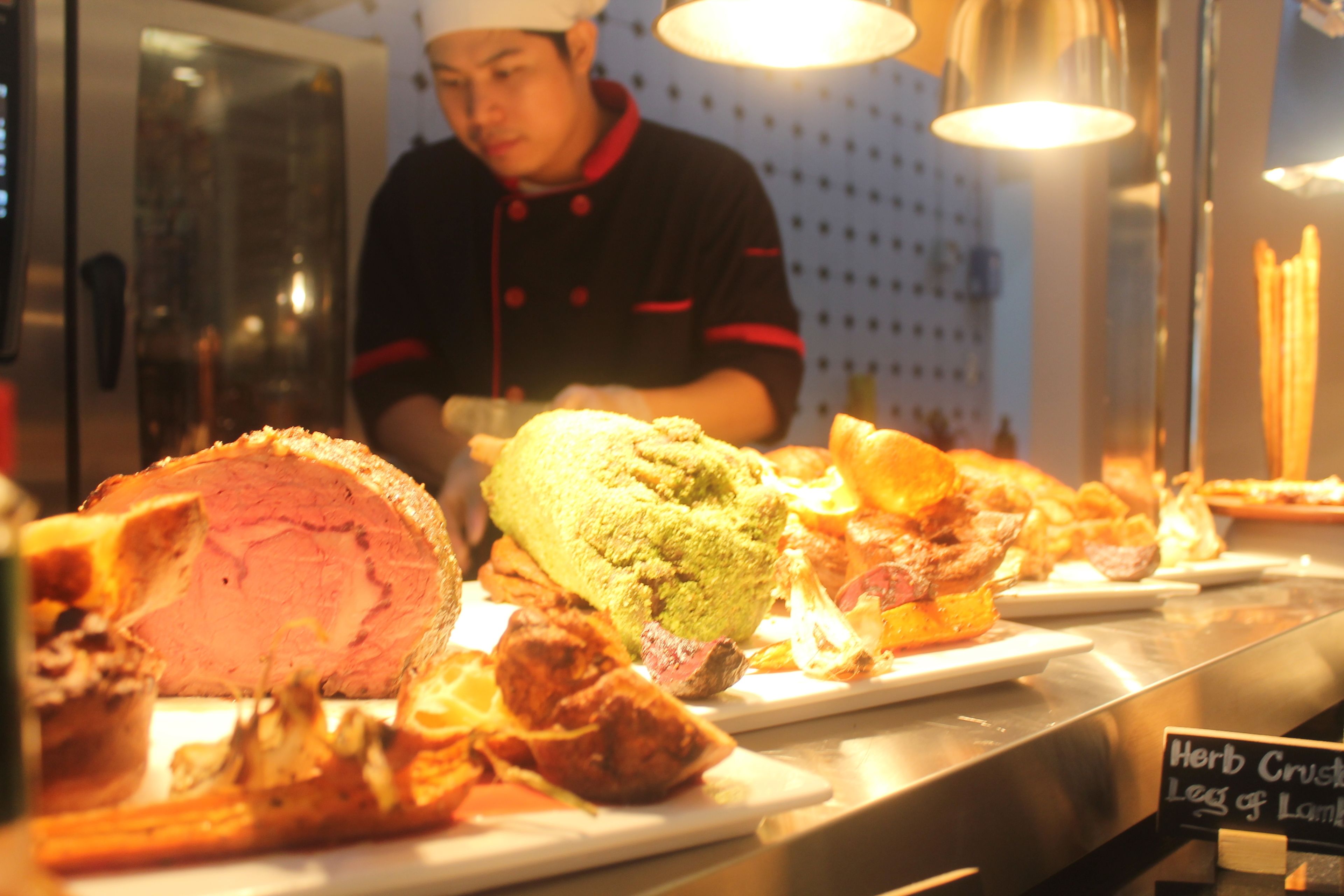 A chef preparing food in a kitchen with various dishes displayed on the counter.