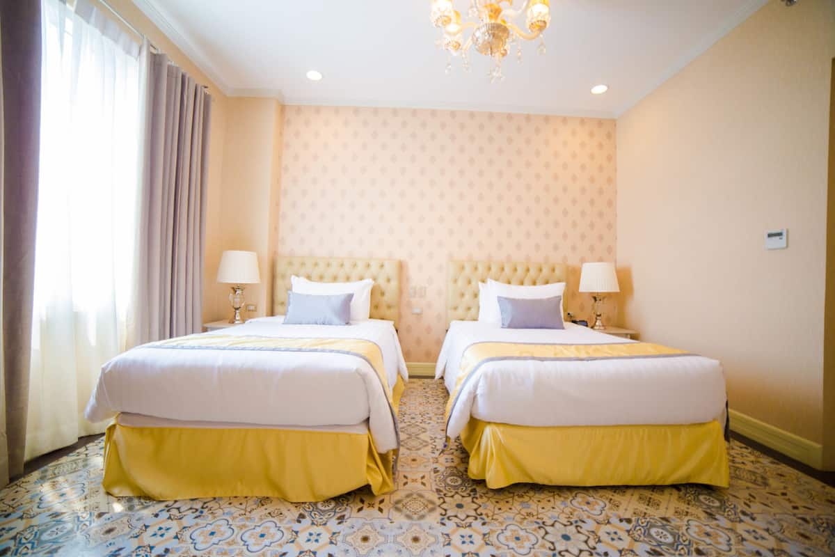 Une chambre d’hôtel avec deux lits, un lustre, un papier peint à motifs et un sol à motifs.