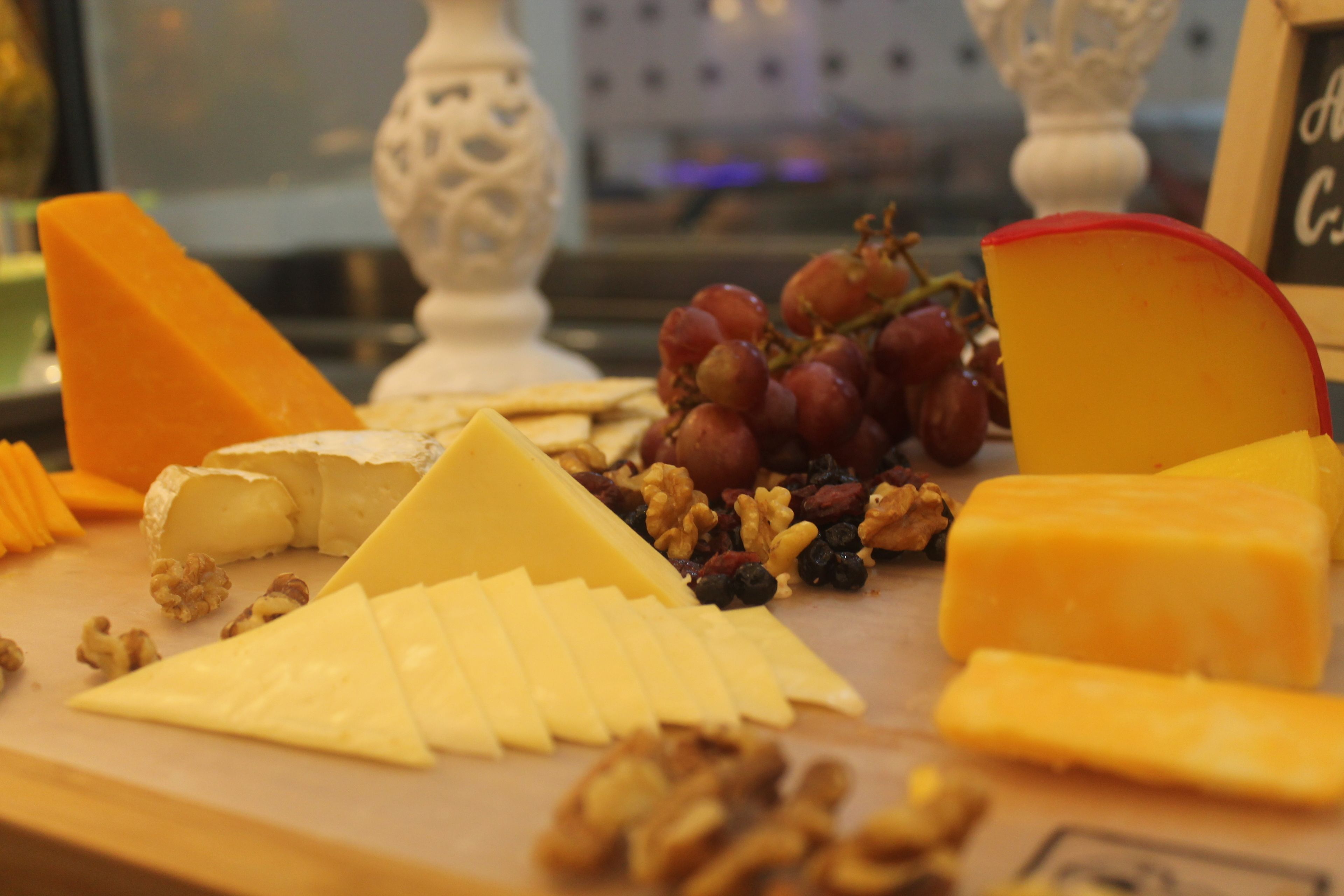 A variety of cheeses and fruits on a wooden board.