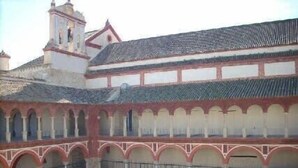 Une cour intérieure avec une fontaine centrale, entourée d’arcades et surmontée d’un toit en tuiles.