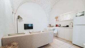 Eine moderne Küche mit Einbauofen, einem Essbereich mit weißem Stuhl und einem an der Wand montierten Fernseher.