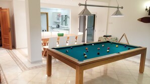 A pool table in a well-lit room with a dining area in the background. - Casa do Mar by Laranjal Rentals (Albufeira)