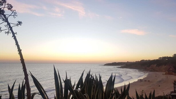 A beach with a clear sky, calm sea, and a few people on the shore. - Casa do Mar by Laranjal Rentals (Albufeira)