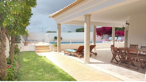 A covered outdoor area with a pool, lounge chairs, and a dining table. - Casa do Mar by Laranjal Rentals (Albufeira)