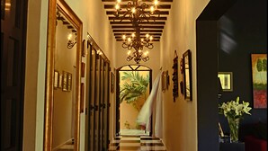 A hotel hallway with a checkered floor, a chandelier, and framed artwork on the walls. - Ochenta Y Dos an urban bed & breakfast (Mérida)