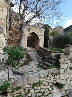 A stone staircase leading up to an arched doorway in a historic building with a tree in the foreground. - Rent House 80 m2 in village at the foot of the Luberon (Robion)