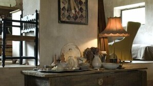 A rustic room with a wooden table, a lamp, and a chair.