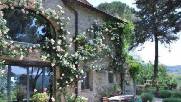 A stone house with a garden patio, outdoor seating, and a view of the countryside.