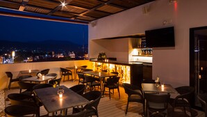 An outdoor dining area with tables and chairs, a bar with bottles, and a TV mounted on the wall. - Real 1900 (Iguala de la Independencia)