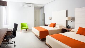 Quarto de hotel com duas camas, uma escrivaninha, uma cadeira e um telefone na mesa de cabeceira.
