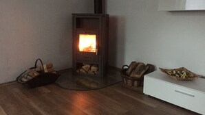 Una habitación con estufa de leña, un armario blanco y una cesta de leña.