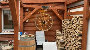 Una cabaña rústica de madera con una rueda grande, un barril y una pila de leña.