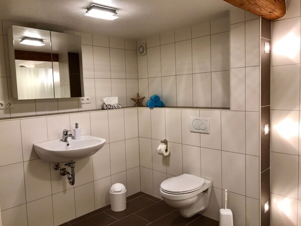 Un baño moderno con lavamanos, inodoro y espejo.