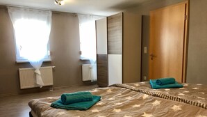 Habitación de hotel con una cama grande, dos toallas, un radiador y una puerta de madera.