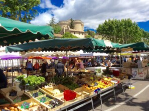 Un marché animé en plein air, avec de nombreux étals proposant des produits frais et divers autres articles.