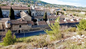 Un bâtiment historique en pierre, doté d’une cour intérieure, entouré d’arbres et bordé par une rivière.