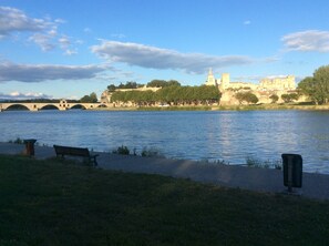 Une vue sur la rivière, avec un pont, un banc et un château en arrière-plan.