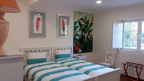 A bedroom with a bed, a nightstand, a chair, a window, and wall art. - Quinta da princesa Barbara (Caldas da Rainha)