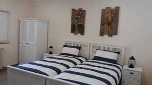 Une chambre à coucher avec un lit double, deux tables de chevet, une armoire et deux œuvres d’art murales.