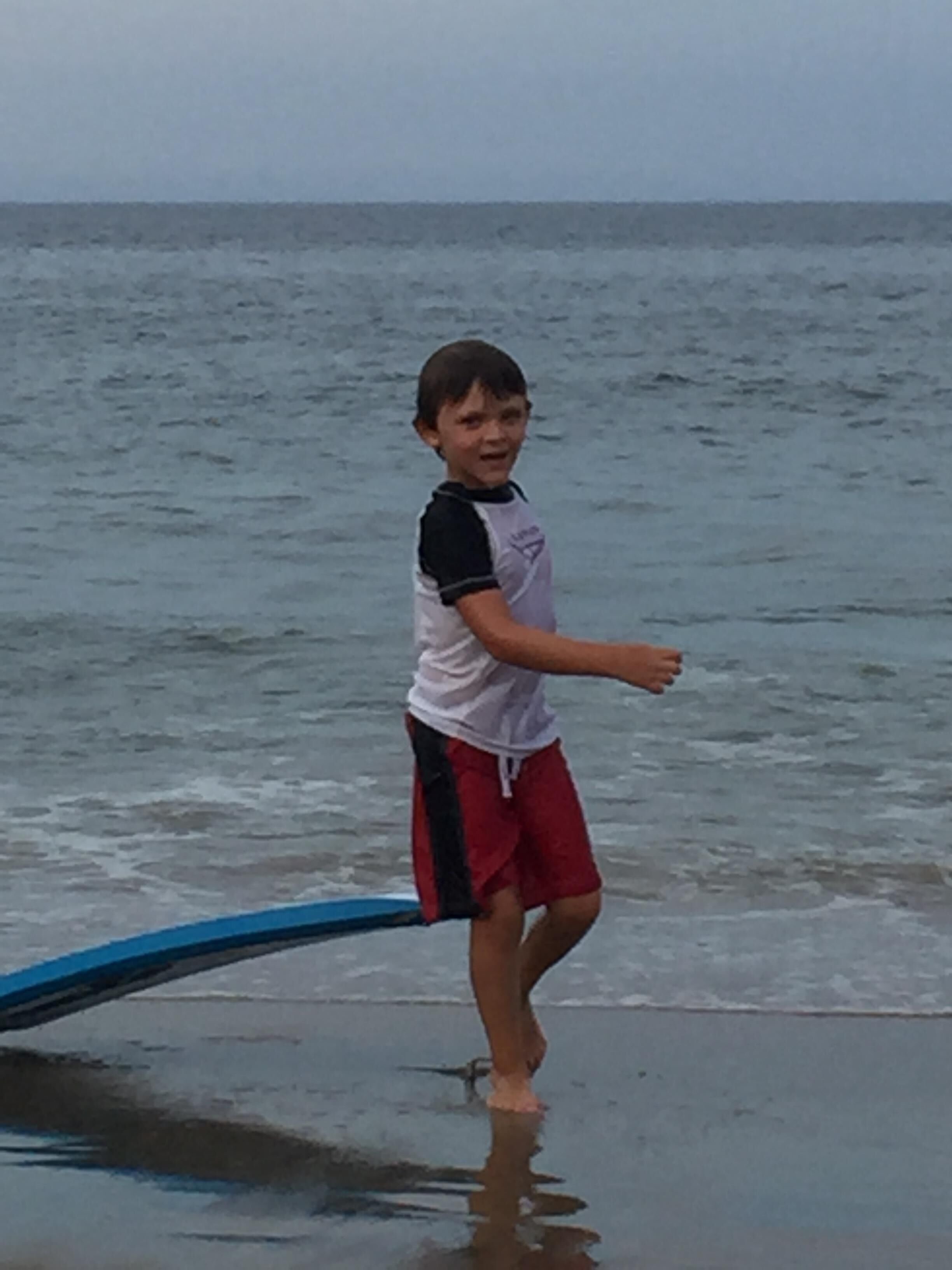 Een kind staat op een surfboard aan het strand.