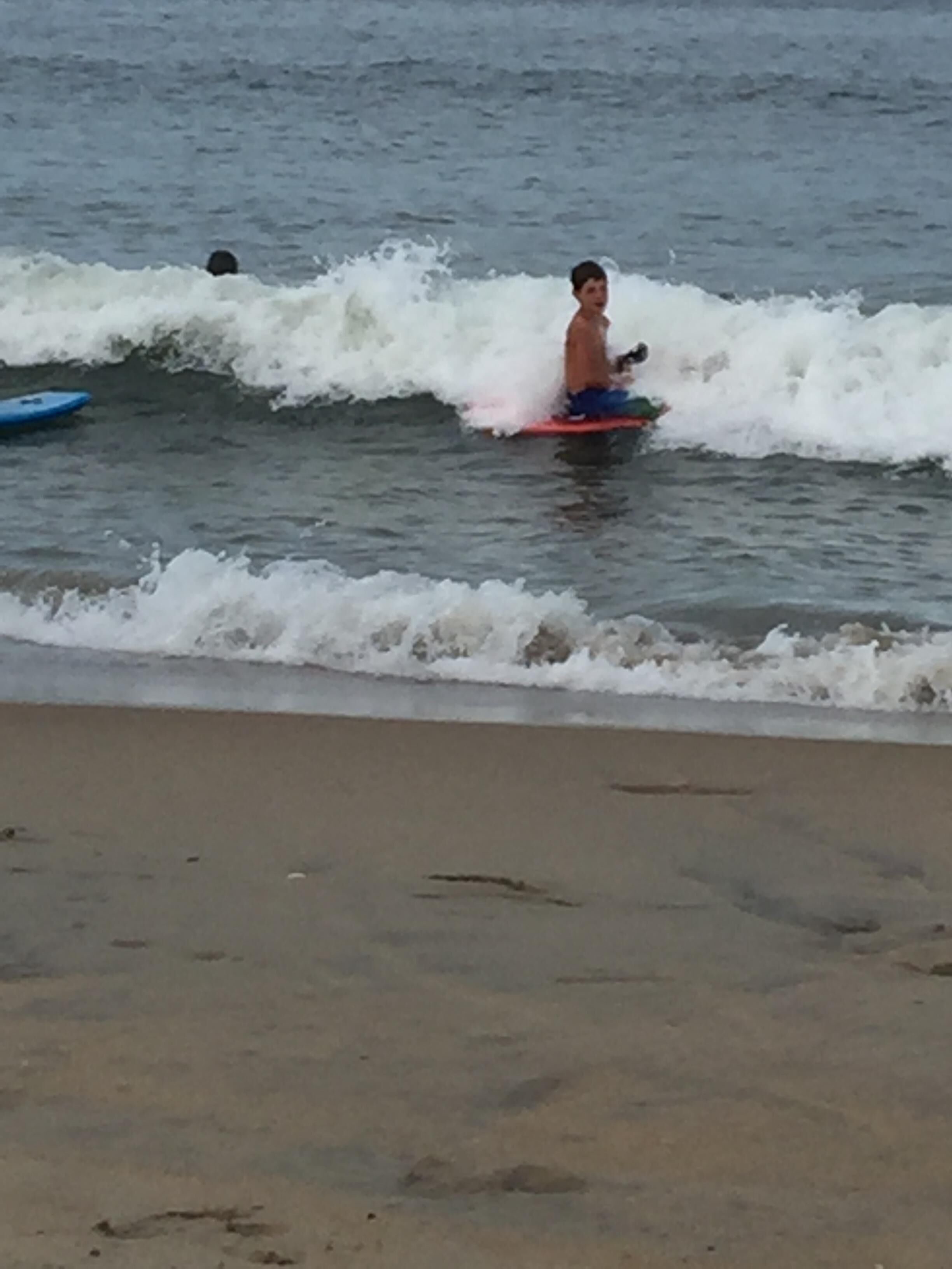 A beach scene with waves and a person on a surfboard.