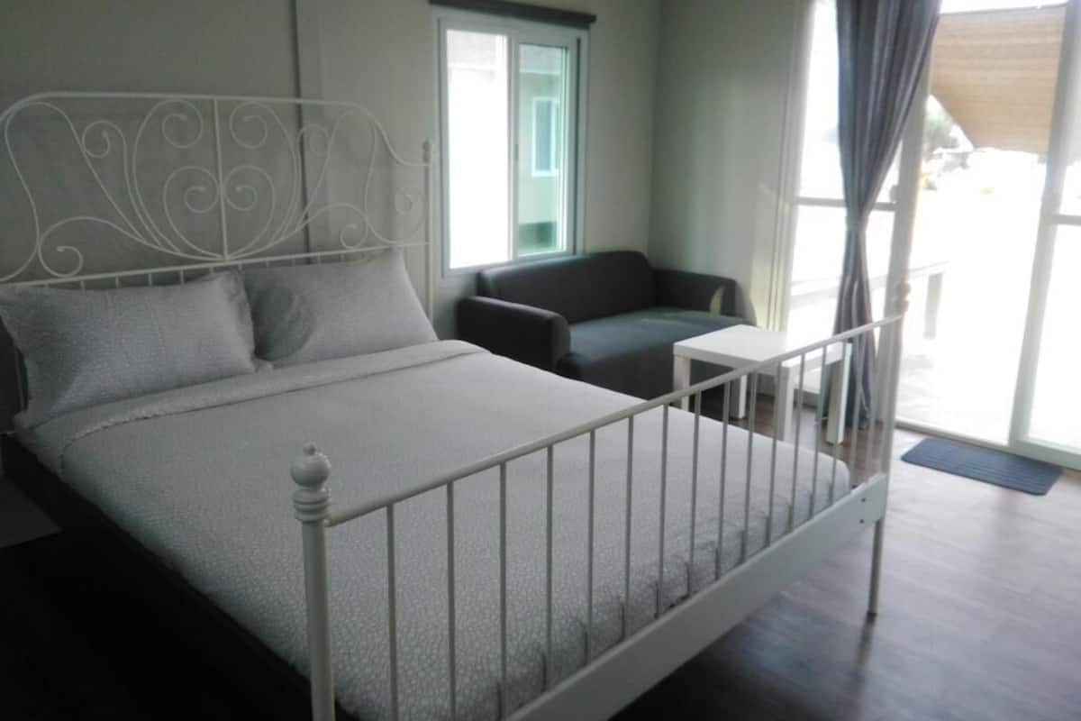 Une chambre à coucher avec un lit, une petite table, une chaise et une fenêtre avec des rideaux.