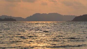 Tramonto su un corpo d'acqua con terre lontane all'orizzonte.