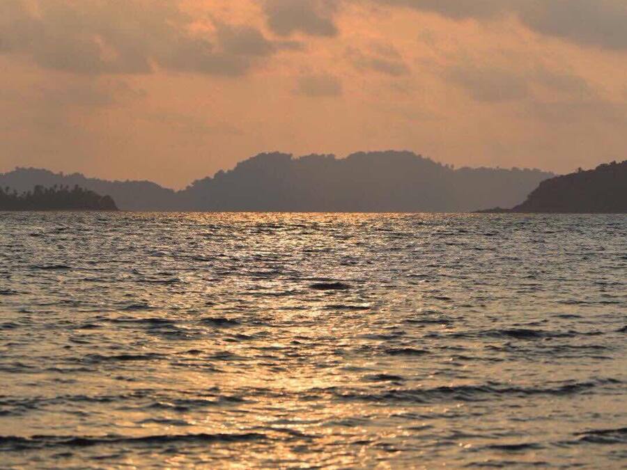 Tramonto su un corpo d'acqua con terre lontane all'orizzonte.