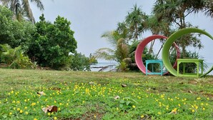 A park with a grassy area, yellow flowers, and a body of water in the background.