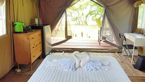 A tented room with a bed, a desk, a chair, and a dresser.