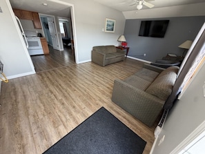 A spacious living area with a sofa, a television, and a kitchen in the background. - Pet Friendly | Walk to Lake | Firepit & Grill (Geneva)