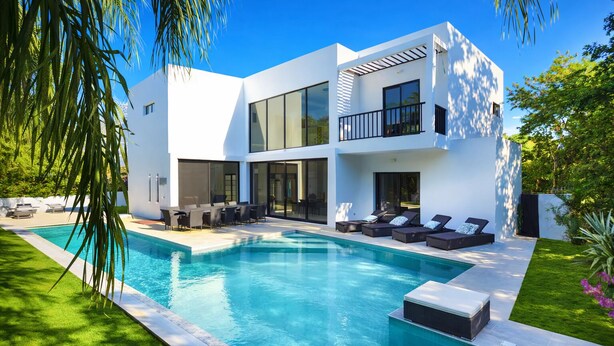 Una casa moderna de dos pisos con piscina, mobiliario exterior y un jardín bien cuidado.