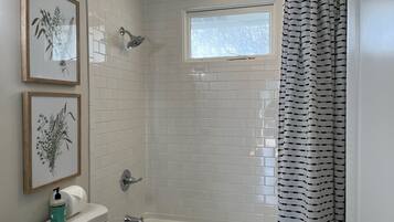 Een bad/douchecombinatie, een haardroger, handdoeken, zeep