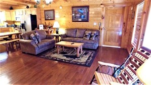 A cozy living room with a wooden floor, a sofa set, a coffee table, and a fireplace. - Aug Special-Mountain View, 2 Suites, Hot Tub, Game Rm, Hammock, Fire Pit + More! (Sevierville)