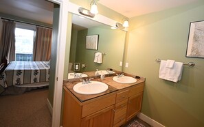 Un baño con dos lavamanos, un espejo grande y un mueble de tocador de madera.