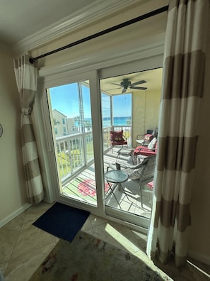 Ein Balkon mit Meerblick, ein Deckenventilator und ein Essbereich mit Stühlen und einem Tisch.