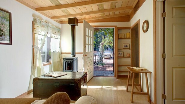 Una habitación acogedora con techo de madera, una maleta antigua, una mesita y una puerta que da al exterior.