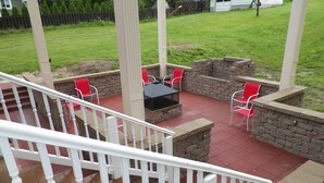 A covered outdoor patio with a stone fire pit, red chairs, and a white railing. - 5 Blocks To The Beach ~ 2 Blocks To Downtown ~ Walk To Everything!   (New Buffalo)