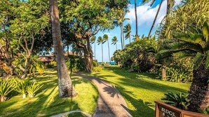 A pathway leading through a lush garden with palm trees and a sign indicating 'Bldgs 4-5'. - A jewel on Oceanfront & Breath Taking Views. (Lahaina)