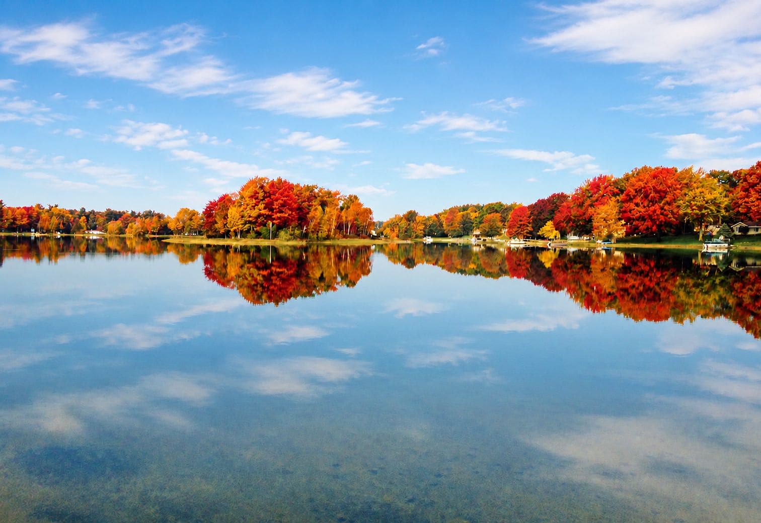 A calm lake with reflections of trees and a clear sky.