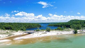 A river with a bridge, surrounded by dense forest and a sandy beach. - Last Open Summer Weekend! August 29th - 31st (Twin Lake)
