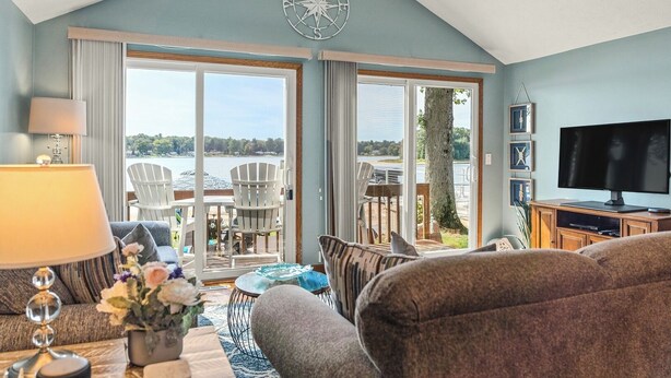 A cozy living room with a large TV, comfortable seating, a coffee table, and a view of the outdoors. - Last Open Summer Weekend! August 29th - 31st (Twin Lake)
